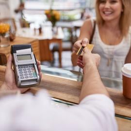 the cafe person holding the card machine giving the card to a women standing in front