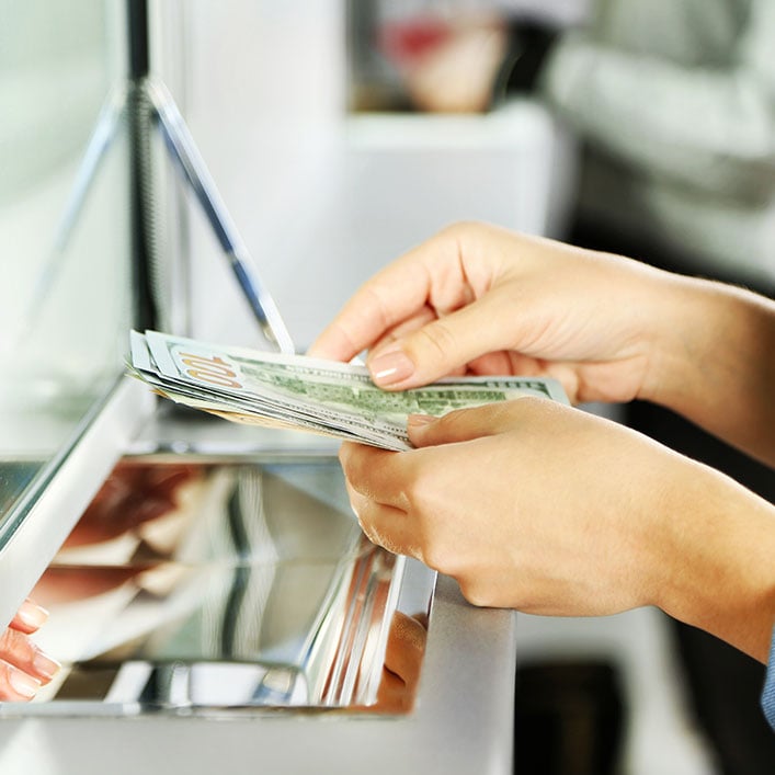 Una mujer depositando dinero en un cajero automático.