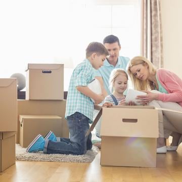 Una familia feliz llevando cajas y muebles a su nuevo hogar, llena de emoción y anticipación.