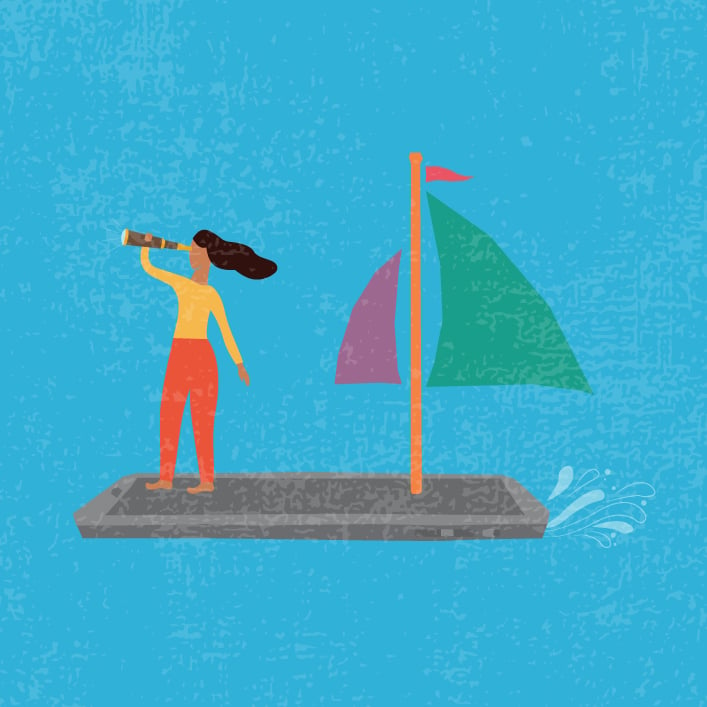 Una mujer de pie en un velero, sosteniendo una vela mientras el barco se desliza por el agua.