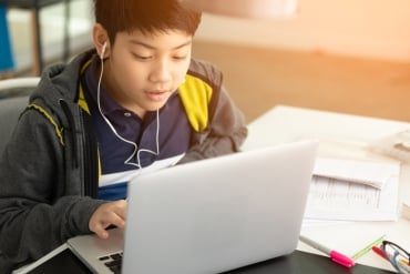 Un chico asiático se concentra en su portátil en un entorno de oficina profesional.