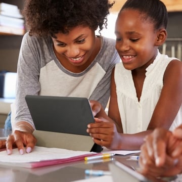 Una madre y su hija se unen a través de una tableta, compartiendo un momento de exploración tecnológica juntas.